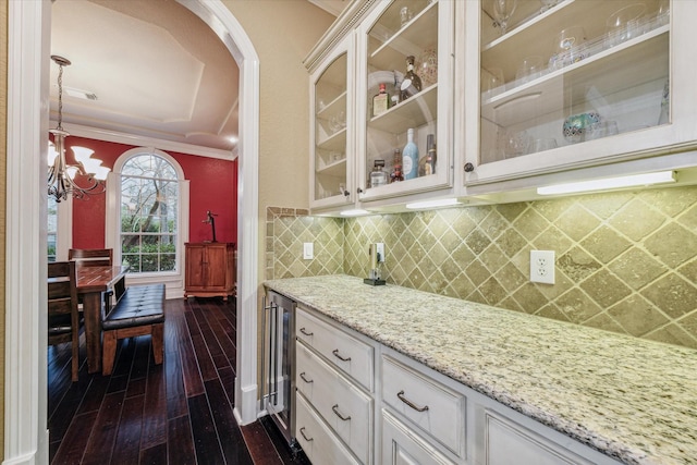 kitchen featuring light stone countertops, beverage cooler, dark hardwood / wood-style flooring, white cabinets, and ornamental molding