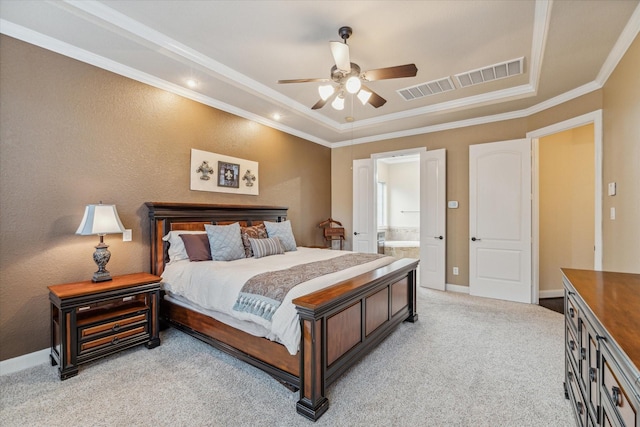 bedroom with connected bathroom, light colored carpet, a tray ceiling, crown molding, and ceiling fan