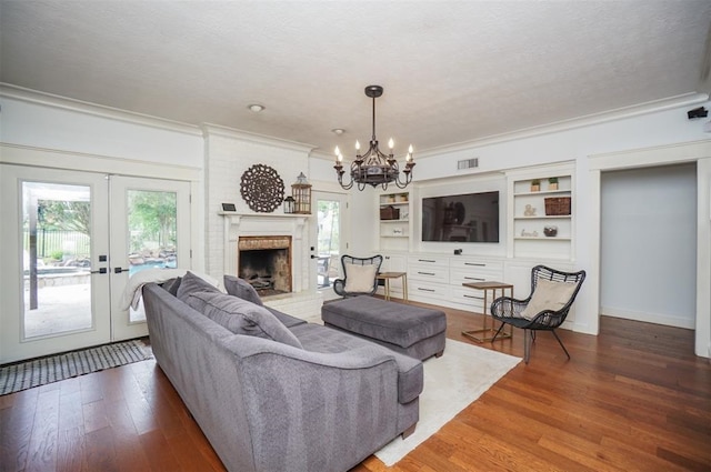 living room with a notable chandelier, french doors, a wealth of natural light, and hardwood / wood-style flooring