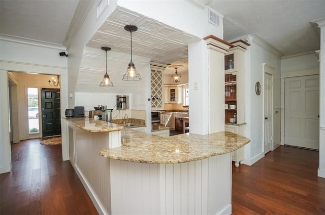 kitchen featuring decorative light fixtures, kitchen peninsula, light stone countertops, and dark hardwood / wood-style floors