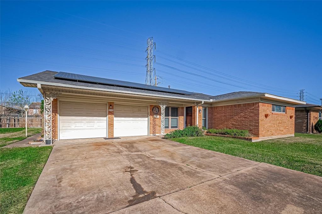 single story home featuring solar panels, a front lawn, and a garage