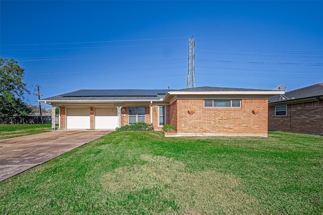 ranch-style home with a garage, a front lawn, and solar panels