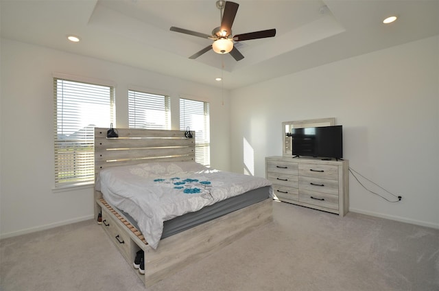 carpeted bedroom with a raised ceiling and ceiling fan