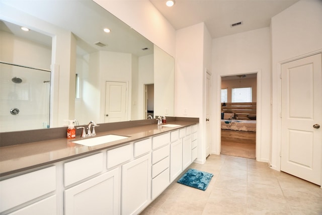 bathroom with a shower with door, vanity, and tile patterned floors