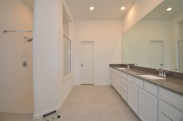 bathroom featuring tile patterned flooring, a tile shower, and vanity