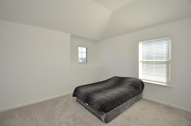 bedroom featuring lofted ceiling, light carpet, and multiple windows