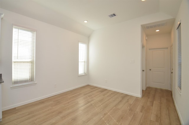 unfurnished room with lofted ceiling and light wood-type flooring