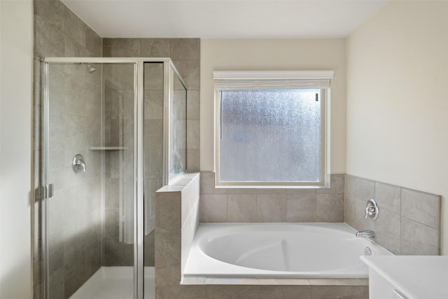 bathroom featuring independent shower and bath, a wealth of natural light, and vanity