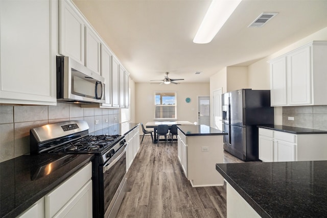 kitchen with a kitchen island, tasteful backsplash, white cabinetry, and stainless steel appliances