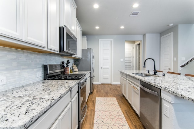 kitchen featuring light stone counters, stainless steel appliances, white cabinets, and sink