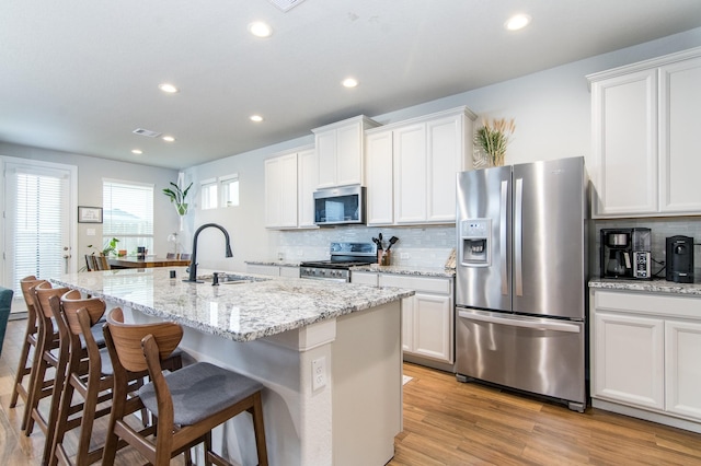 kitchen featuring white cabinets, a kitchen island with sink, and appliances with stainless steel finishes