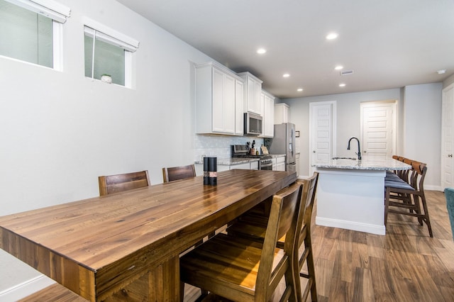 dining space featuring sink and dark wood-type flooring