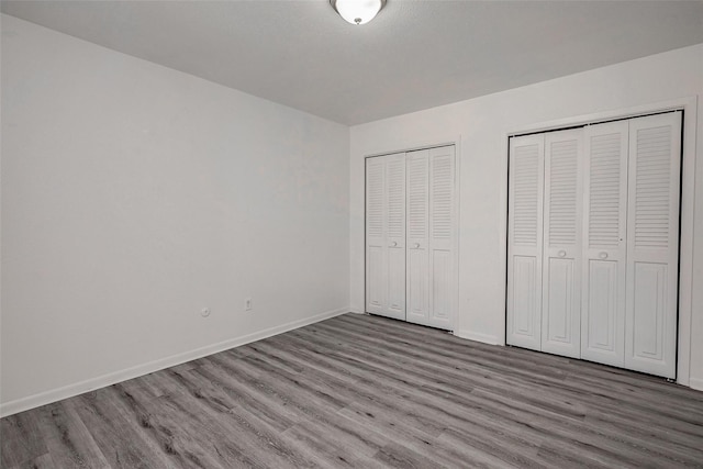 unfurnished bedroom with wood-type flooring and two closets