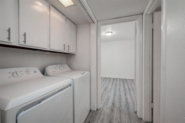 clothes washing area with cabinets, light hardwood / wood-style flooring, and washer and clothes dryer