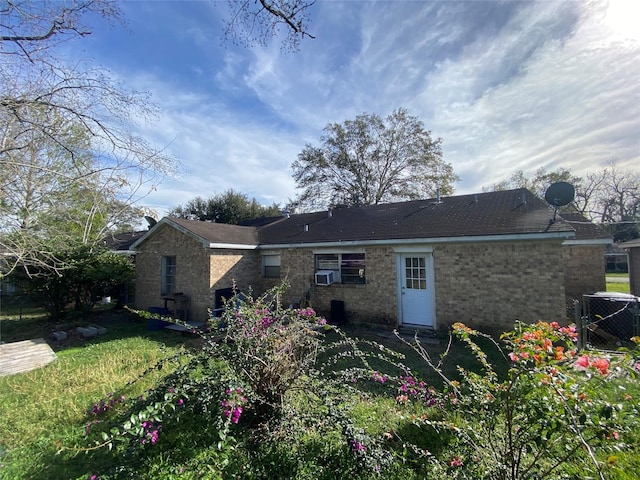 back of house featuring central air condition unit, cooling unit, and a lawn