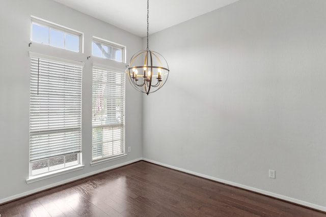 spare room featuring a notable chandelier and dark wood-type flooring