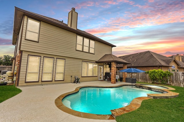 pool at dusk with a gazebo, an in ground hot tub, and a patio area