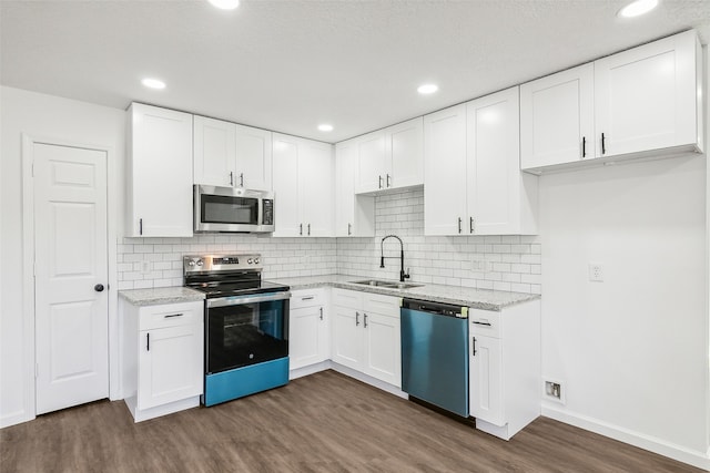 kitchen featuring light stone countertops, dark hardwood / wood-style flooring, white cabinets, appliances with stainless steel finishes, and sink