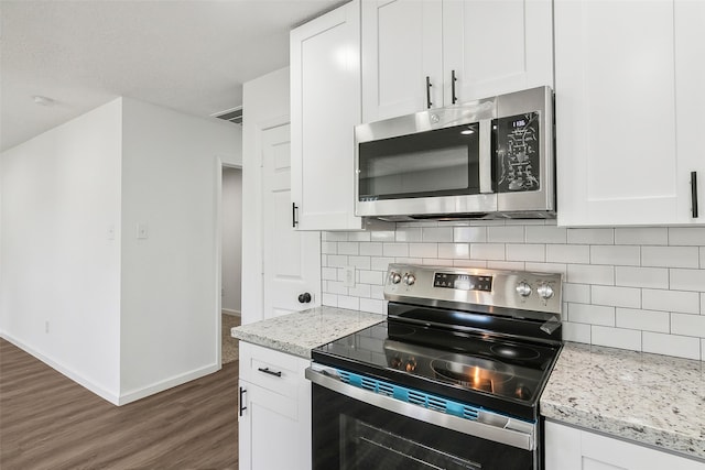 kitchen featuring light stone counters, stainless steel appliances, and white cabinetry