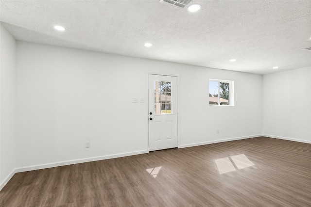 unfurnished room with dark wood-type flooring and a textured ceiling