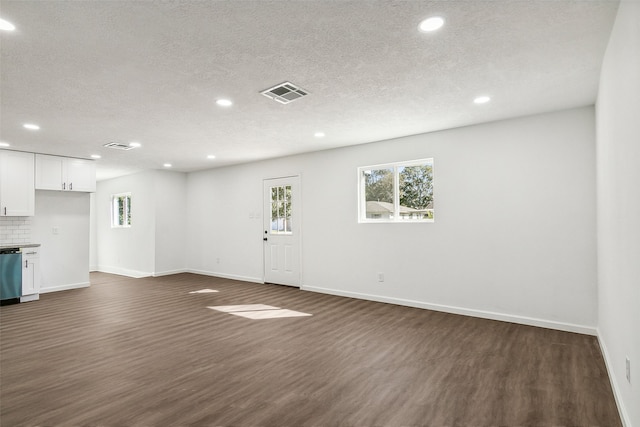 unfurnished living room with a textured ceiling and dark hardwood / wood-style flooring