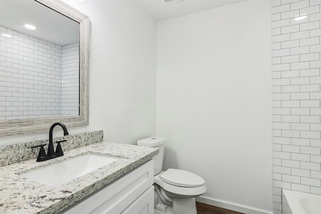 full bathroom featuring hardwood / wood-style flooring, tiled shower / bath combo, vanity, and toilet