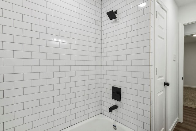 bathroom with wood-type flooring and tiled shower / bath