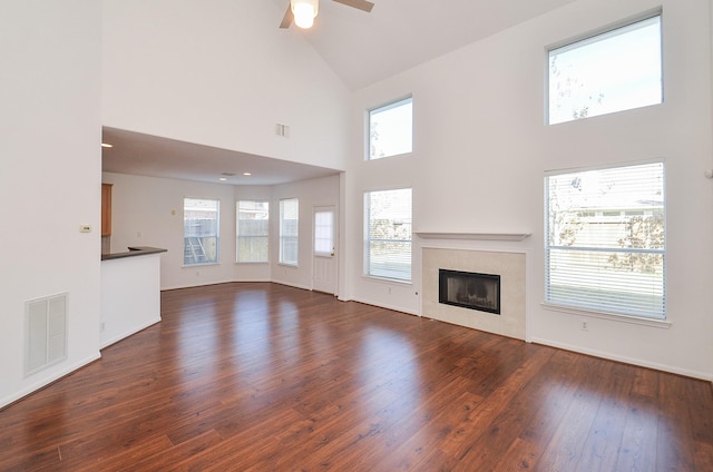 unfurnished living room with high vaulted ceiling, dark wood-type flooring, and ceiling fan