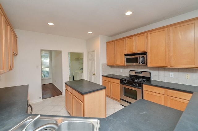 kitchen with washing machine and dryer, backsplash, light tile patterned flooring, and stainless steel appliances