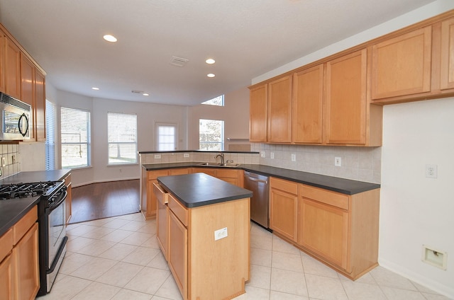 kitchen with appliances with stainless steel finishes, a kitchen island, sink, backsplash, and kitchen peninsula