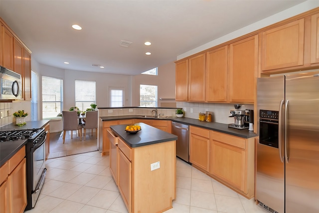 kitchen with appliances with stainless steel finishes, a center island, sink, kitchen peninsula, and light tile patterned floors