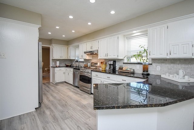 kitchen featuring kitchen peninsula, white cabinetry, dark stone countertops, and stainless steel appliances