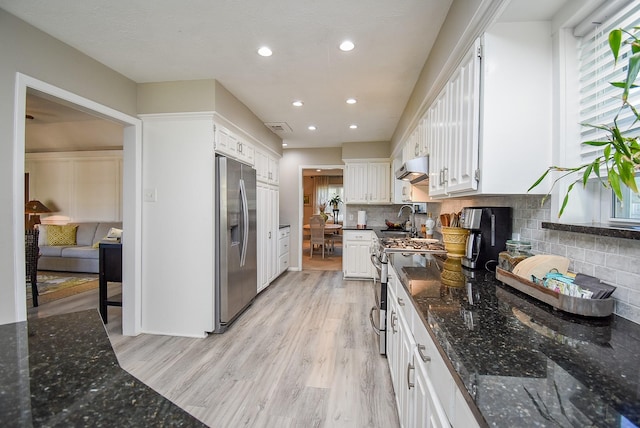 kitchen featuring white cabinets, dark stone countertops, light hardwood / wood-style floors, backsplash, and appliances with stainless steel finishes