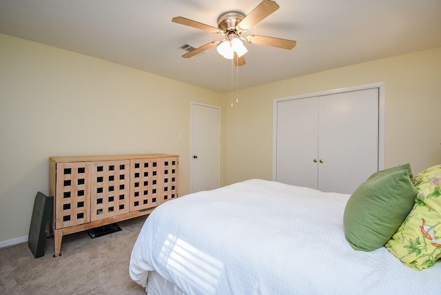 bedroom featuring light colored carpet, ceiling fan, and a closet