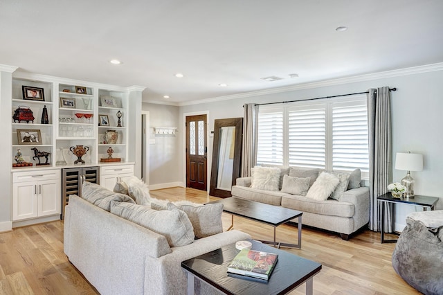 living room featuring beverage cooler, ornamental molding, bar, and light hardwood / wood-style flooring