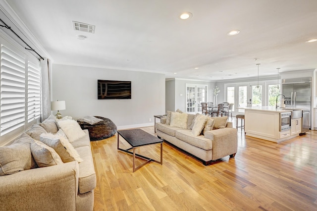 living room featuring light wood-type flooring, crown molding, and french doors