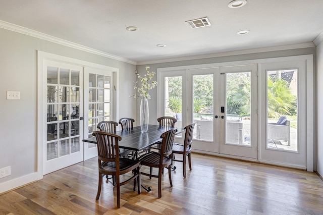 dining room with french doors, crown molding, and light hardwood / wood-style floors