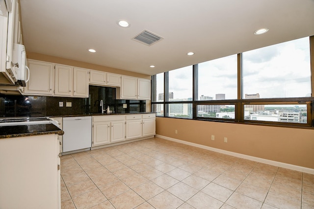 kitchen featuring sink, white dishwasher, white cabinets, and dark stone countertops