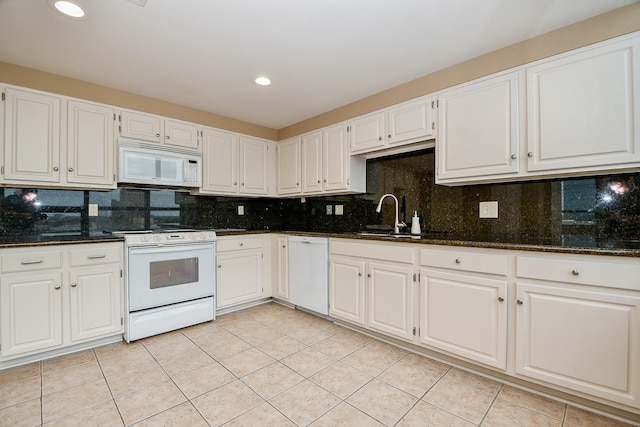 kitchen featuring white appliances, dark stone counters, white cabinetry, and sink