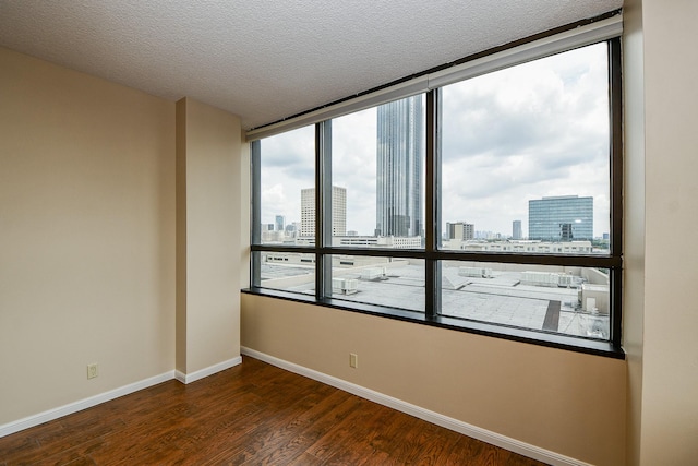 unfurnished room with a textured ceiling and dark hardwood / wood-style floors