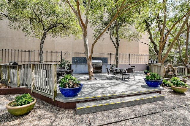 wooden terrace featuring an outdoor kitchen and a patio area