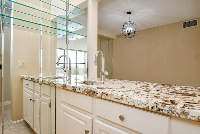 kitchen with sink, pendant lighting, a notable chandelier, and light stone counters