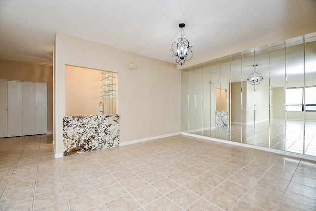 unfurnished room with a textured ceiling, tile patterned flooring, and a chandelier