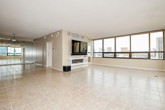 unfurnished living room with an inviting chandelier and light tile patterned floors