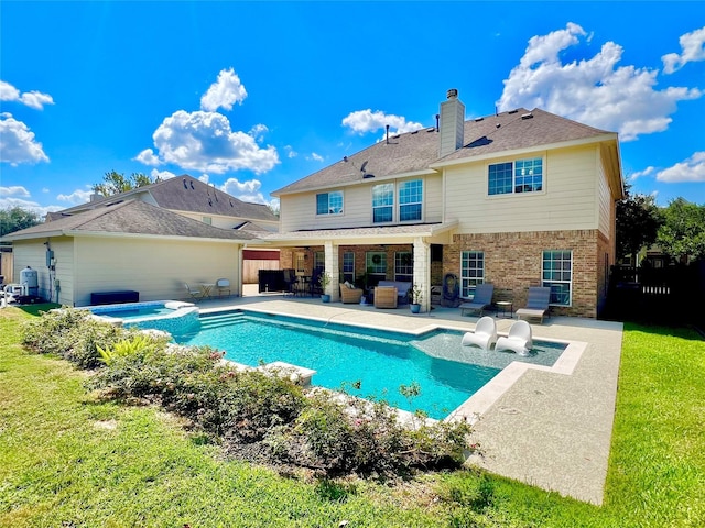 back of property with a patio area, a swimming pool with hot tub, and a lawn