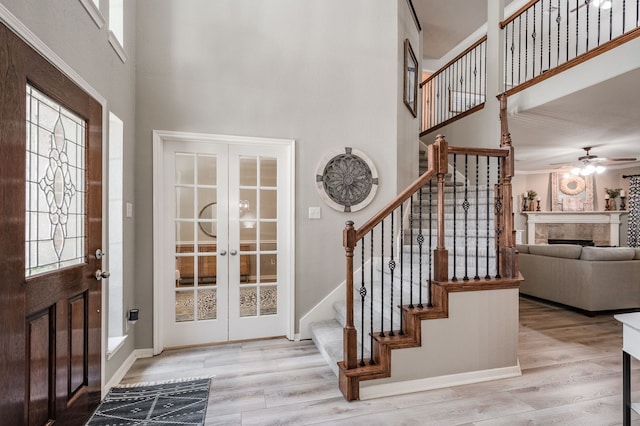 foyer entrance featuring a towering ceiling, french doors, a healthy amount of sunlight, and light hardwood / wood-style flooring