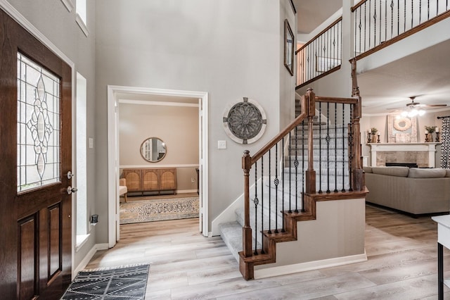 entryway with a high ceiling, ceiling fan, and light hardwood / wood-style floors