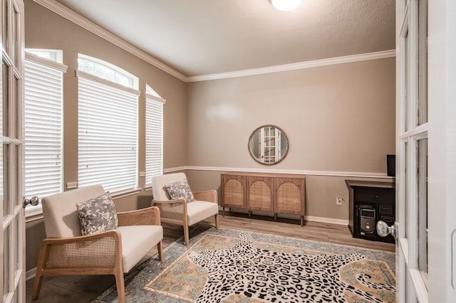 sitting room with wood-type flooring, a healthy amount of sunlight, and crown molding