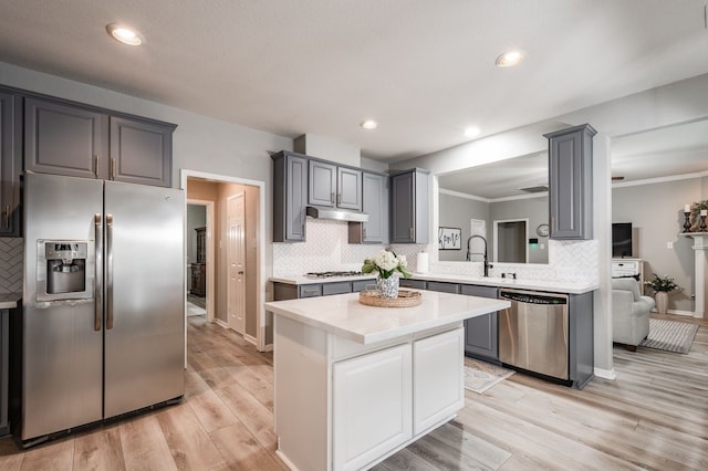 kitchen featuring stainless steel appliances, a center island, light hardwood / wood-style floors, backsplash, and gray cabinetry