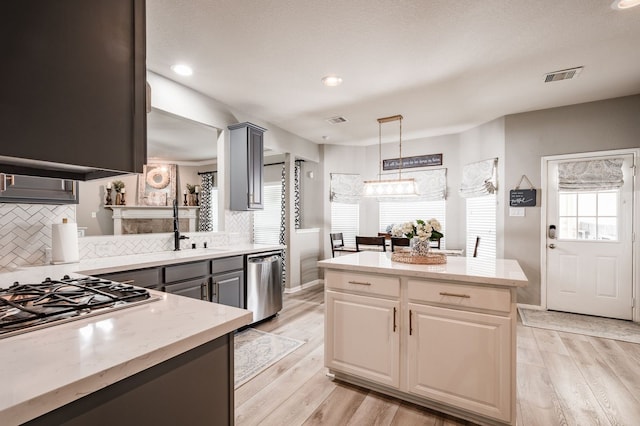 kitchen featuring appliances with stainless steel finishes, pendant lighting, light hardwood / wood-style flooring, and tasteful backsplash